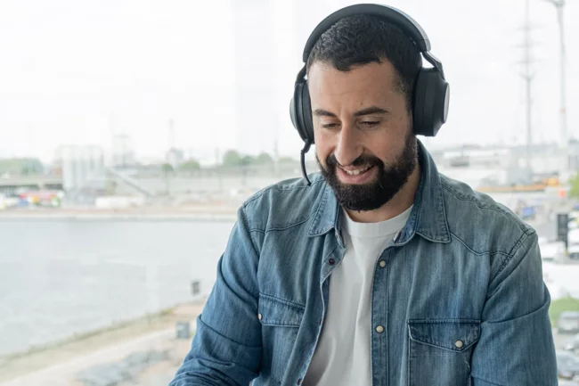 Man wearing a headset, sitting at a desk and participating in a call.